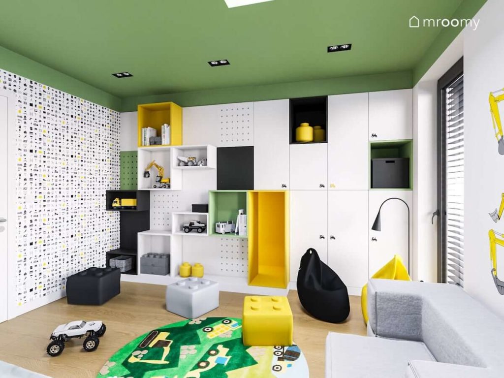 pokój chłopca z biało czarno żółto zieloną szafą i regałami na zamówienie i tapetą z koparkami i symbolami budowlanymi i z pufami w kształcie klocków lego