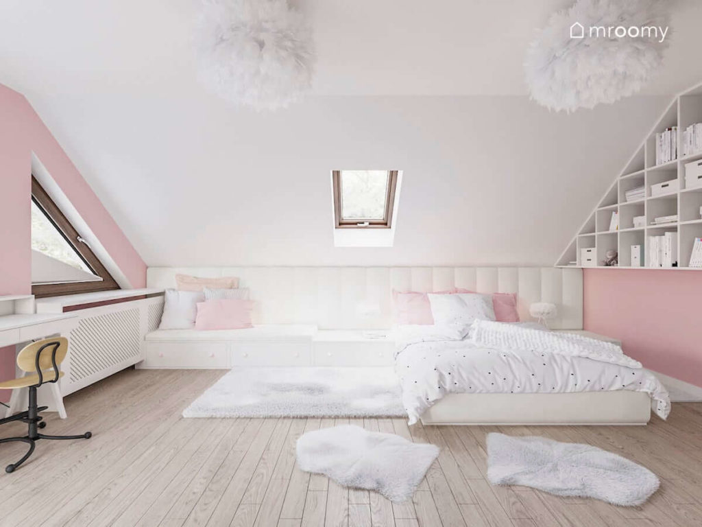 Duże łóżko z tapicerowanym wezgłowiem w biało różowym pokoju ze skosami dla dziewczynki