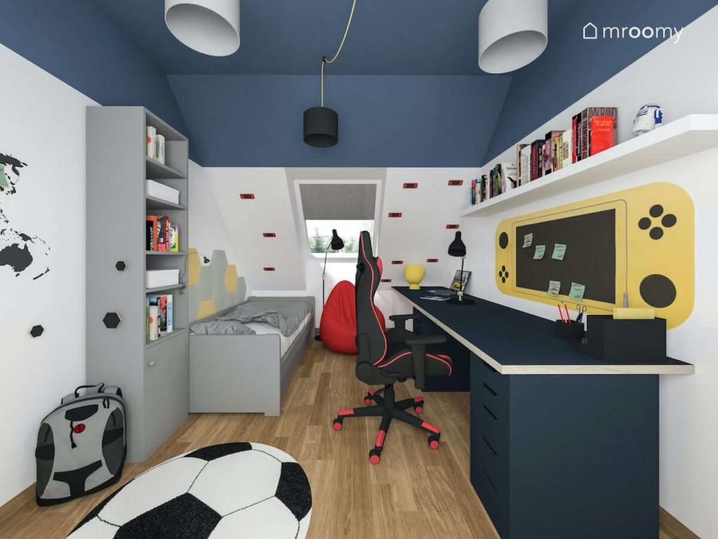 Poddaszowy pokój dla nastolatka z gamingowym fotelem szarymi meblami i granatowym sufitem