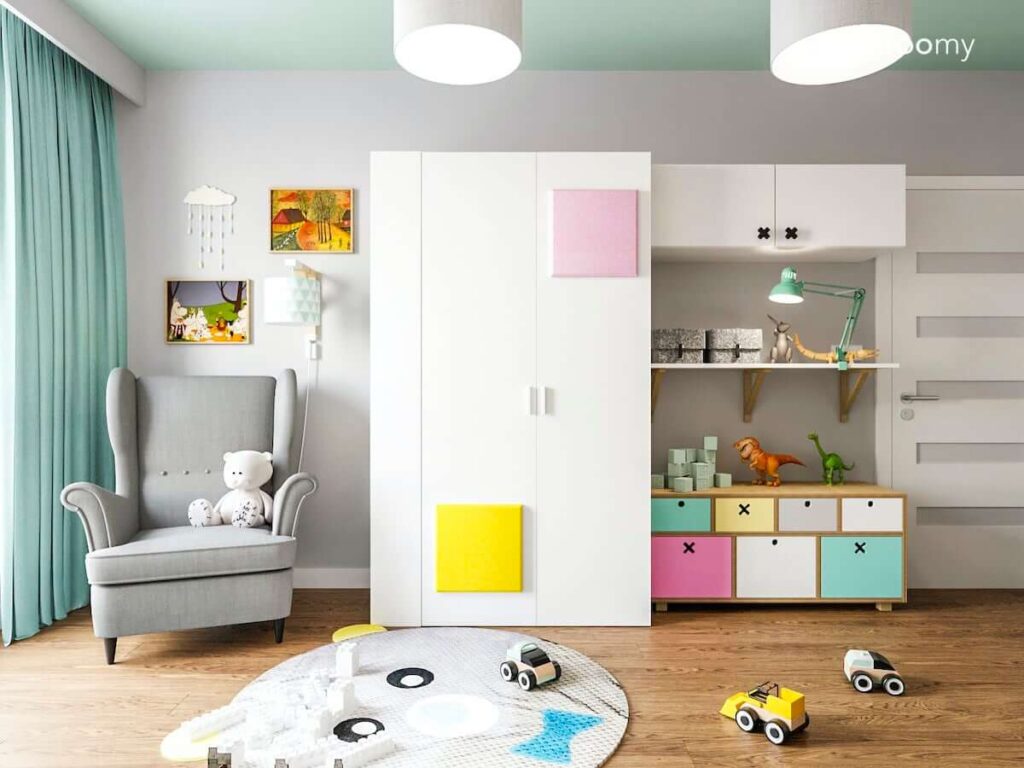 Szafa ozdobiona kolorowymi panelami ściennymi komoda z szufladami oraz fotel i dywan w kształcie misia w pokoju chłopca i dziewczynki