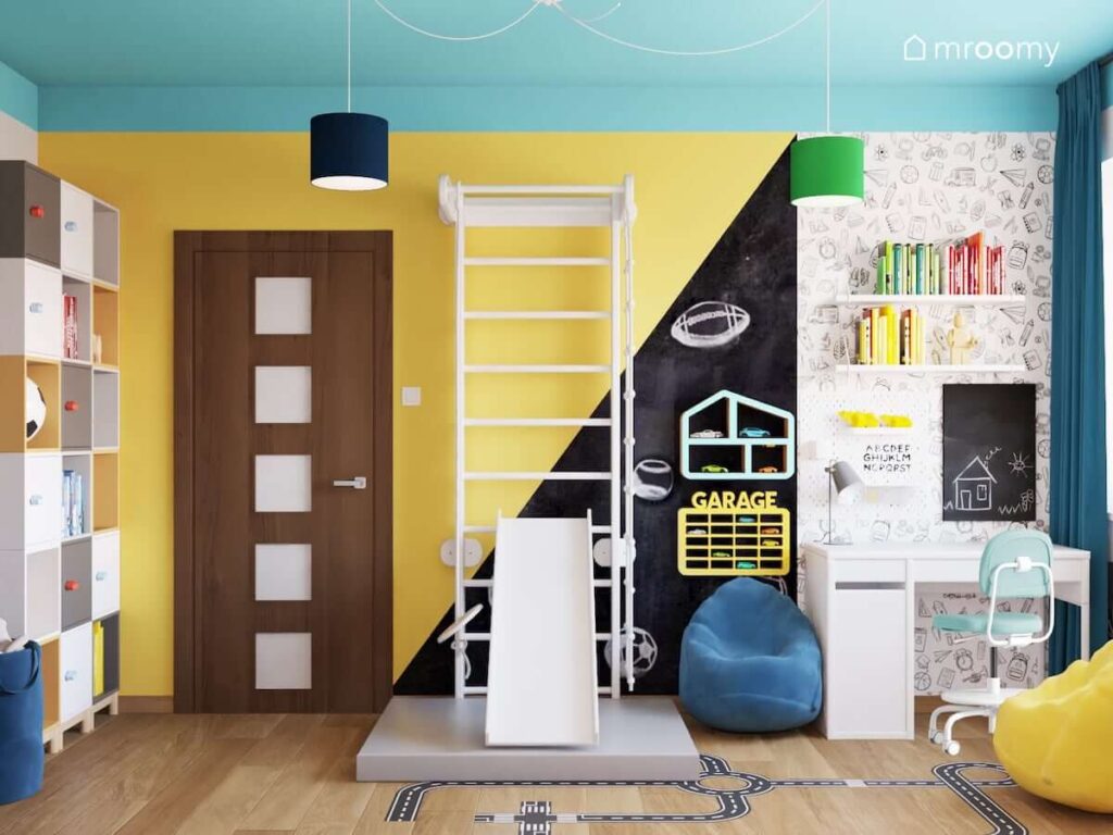 Kolorowy pokój dla rodzeństwa z drabinką gimnastyczną ze zjeżdżalnią kolorowymi półkami na zabawki pufą sako oraz biurkiem nad którym znajdują się organizery i półki na książki