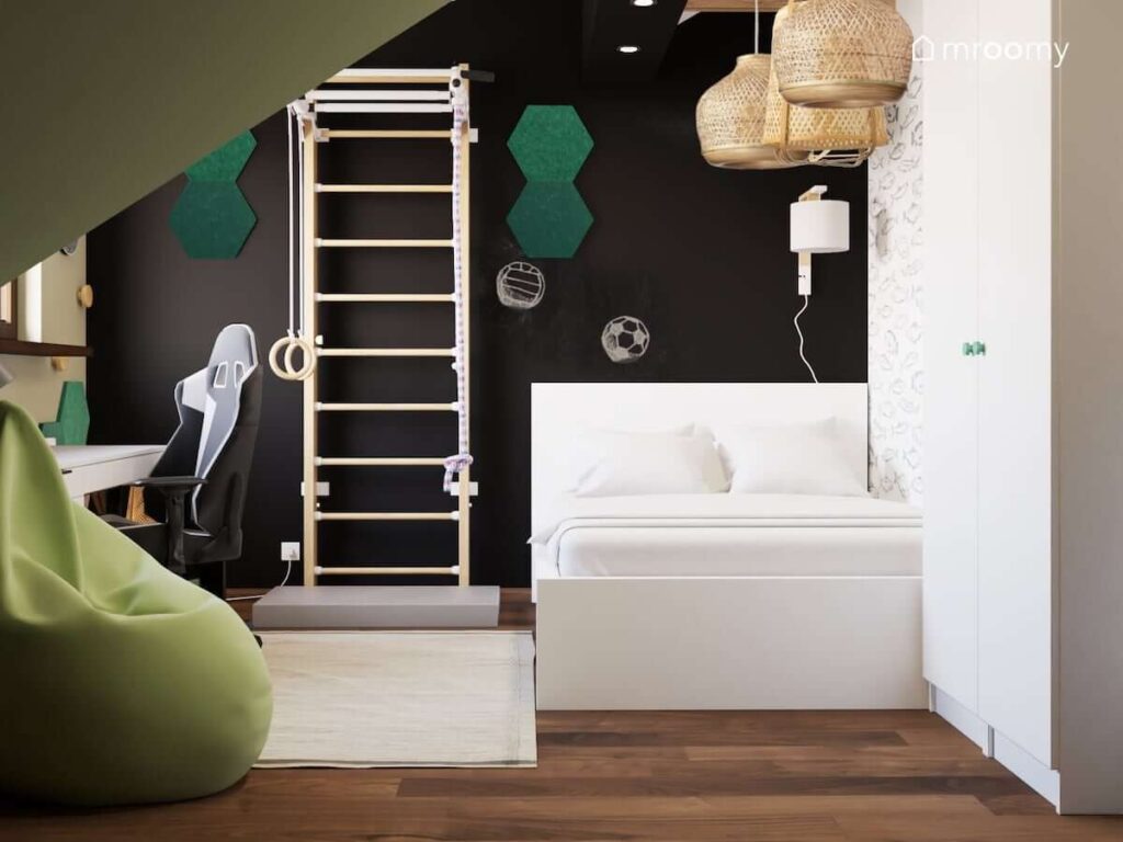 Czarno zielono biały pokój dla chłopca w wieku szkolnym z białym łóżkiem drabinką gimnastyczną oraz szafą pomalowaną farbą tablicową i ozdobioną zielonymi panelami ściennymi