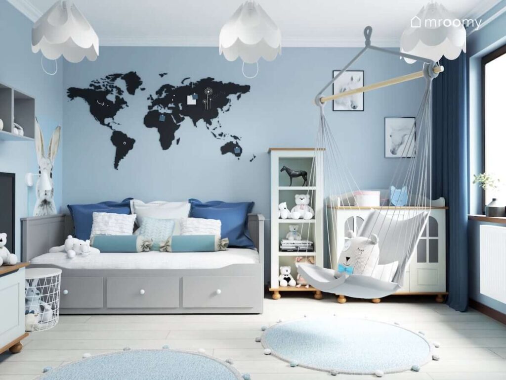 Niebieski pokój dla dziewczynki z szarym łóżkiem z szufladami białymi meblami tablicą magnetyczno kredową w kształcie mapy świata oraz wiszącym fotelem