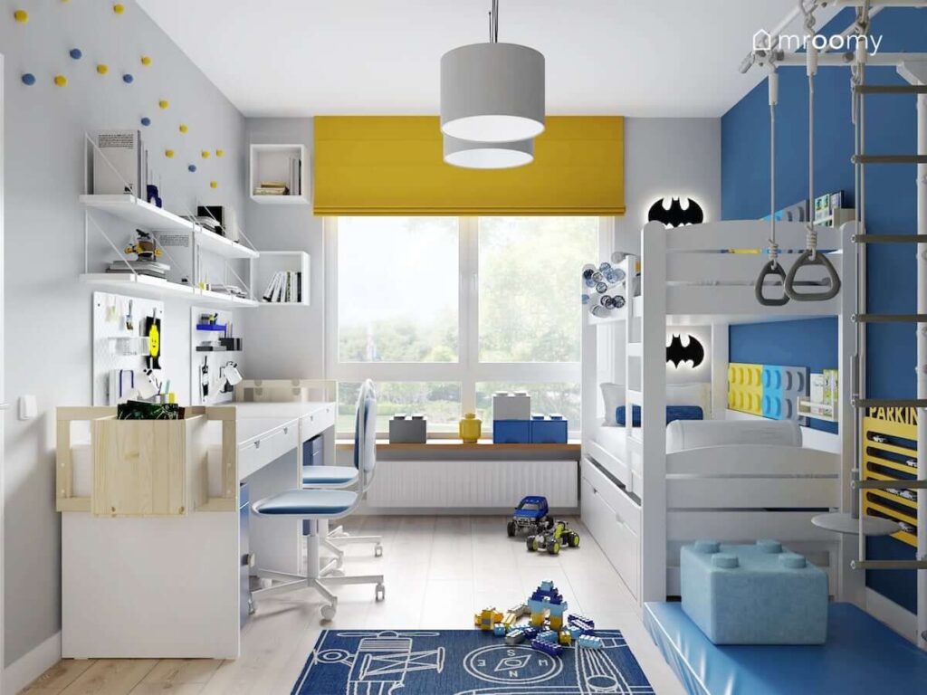 Pokój dla dwóch chłopców z białymi i niebieskimi ścianami oraz żółtymi dodatkami a także z białym łóżkiem piętrowym i strefą nauki z dwoma biurkami z drewnianymi dostawkami
