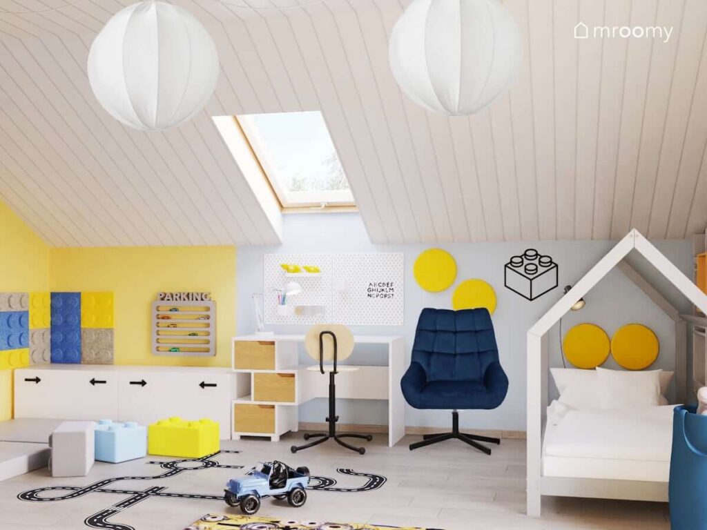 Biało żółty poddaszowy pokój dla chłopca z łóżkiem w kształcie domku biurkiem z drewnianymi szufladami oraz lampami z oryginalnymi kloszami