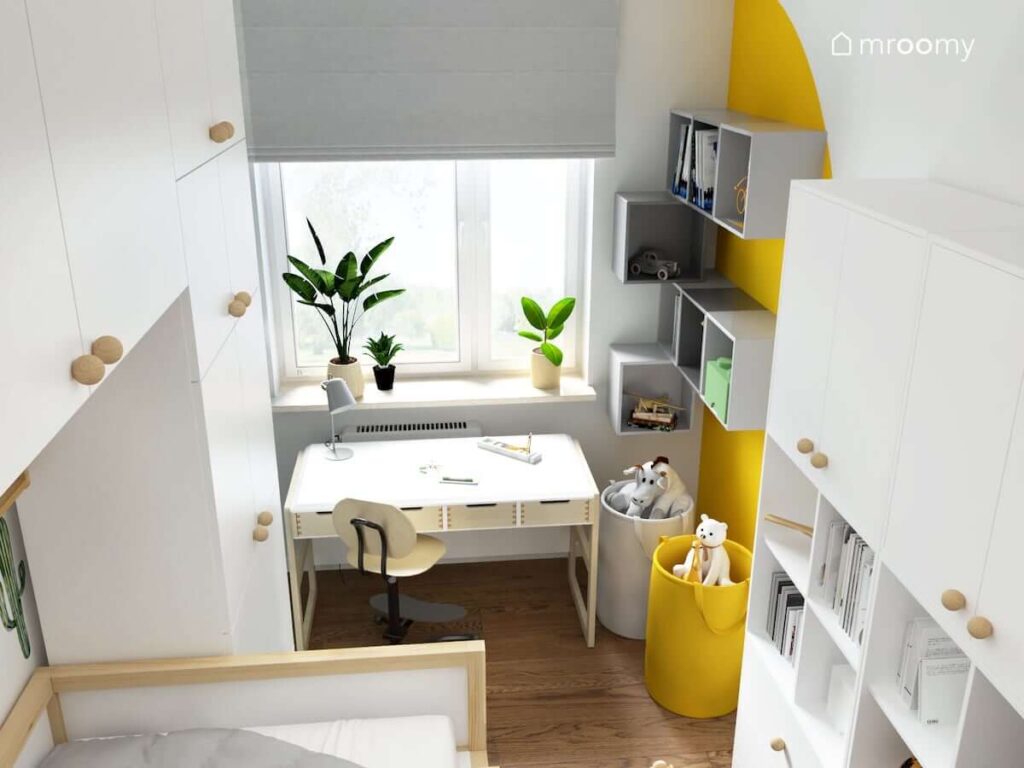 Biało żółty pokój dla chłopca z biało drewnianym biurkiem szarymi szafkami ściennymi oraz białą szafą i regałem