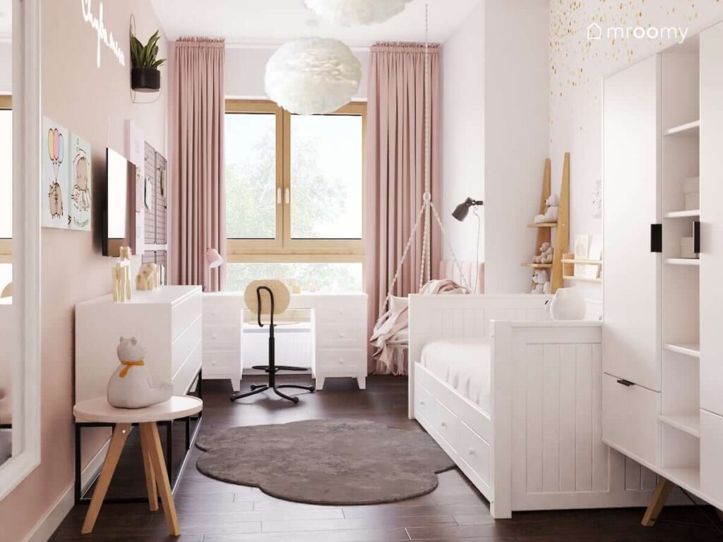 Delikatny biało różowy pokój dla dziewczynki z białym łóżkiem szafą na drewnianych nogach oraz biurkiem z dwoma komodami