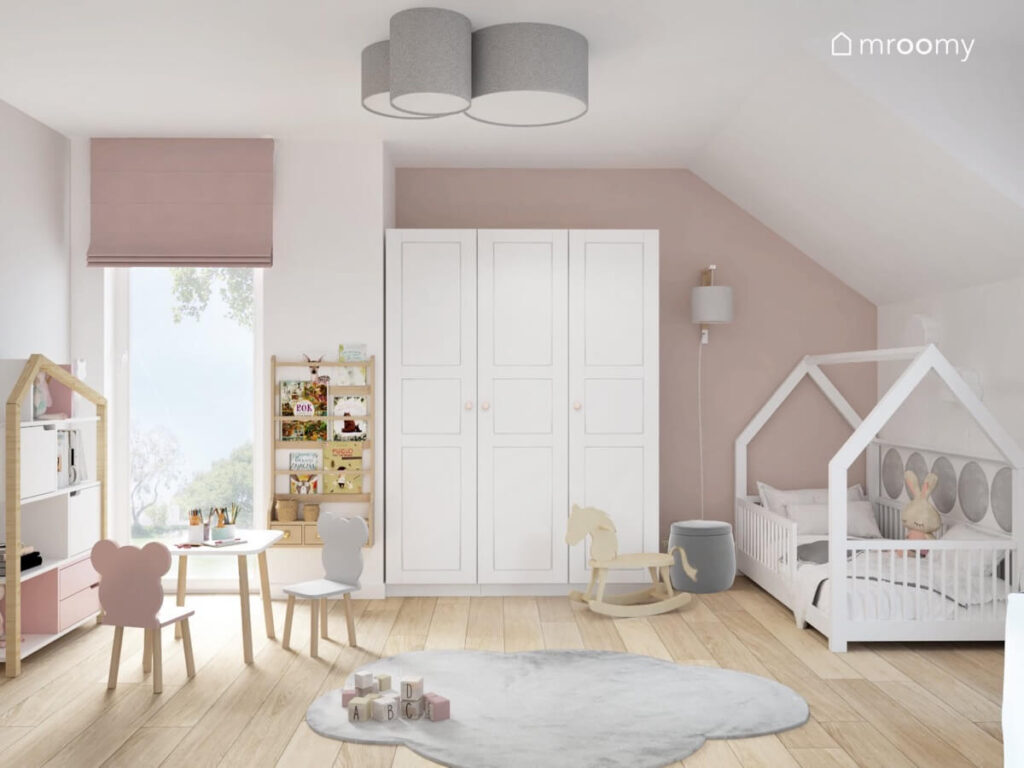 Biało różowy pokój dziewczynki a w nim łóżko domek biała szafa stolik z krzesełkami w kształcie misiów i dywanik w kształcie chmurki