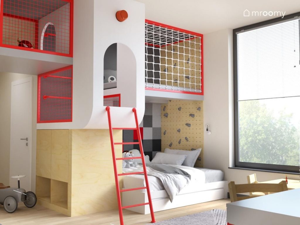 Czerwona drabina prowadząca na obszerną antresolę w pokoju dla chłopca a także miejsce do spania wyłożone panelami ściennymi i z którego po ściance wspinaczkowej również można dostać się na antresolę
