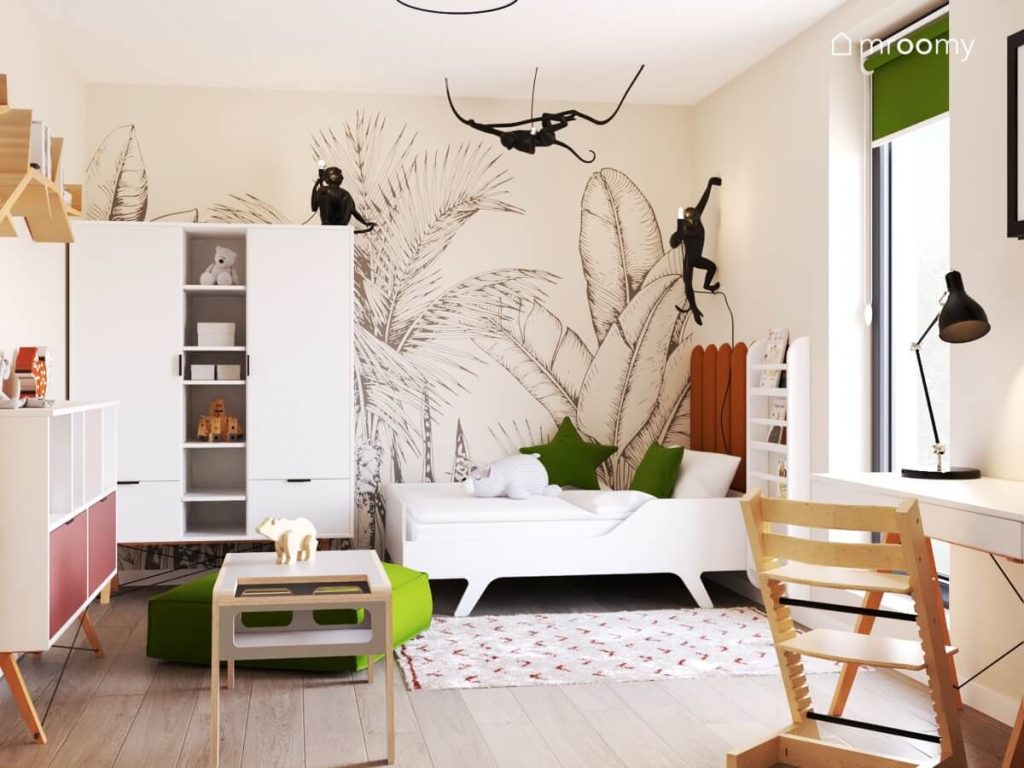 Jasny pokój dla małej dziewczynki z białym łóżkiem i szafą tapetą w liście oraz lampami w kształcie rozbrykanych małpek