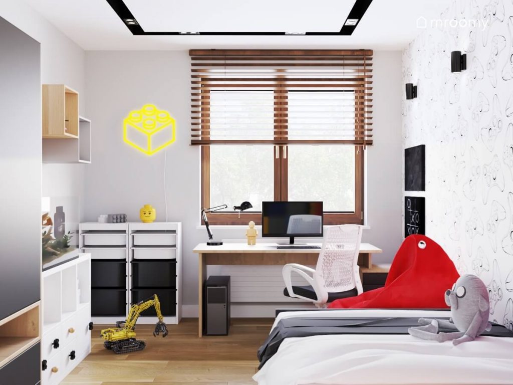 Jasny pokój dla chłopca w wieku szkolnym a w nim biało czarno drewniane meble czerwony worek sako oraz ledon w kształcie klocka