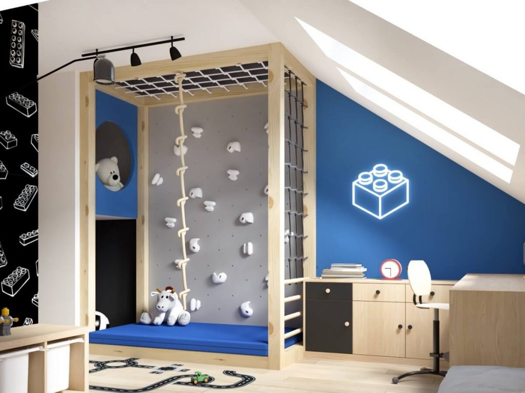 Szara ścianka wspinaczkowa z białymi uchwytami oraz lina i siatka do wspinania a także niebieski materac w pokoju czterolatka