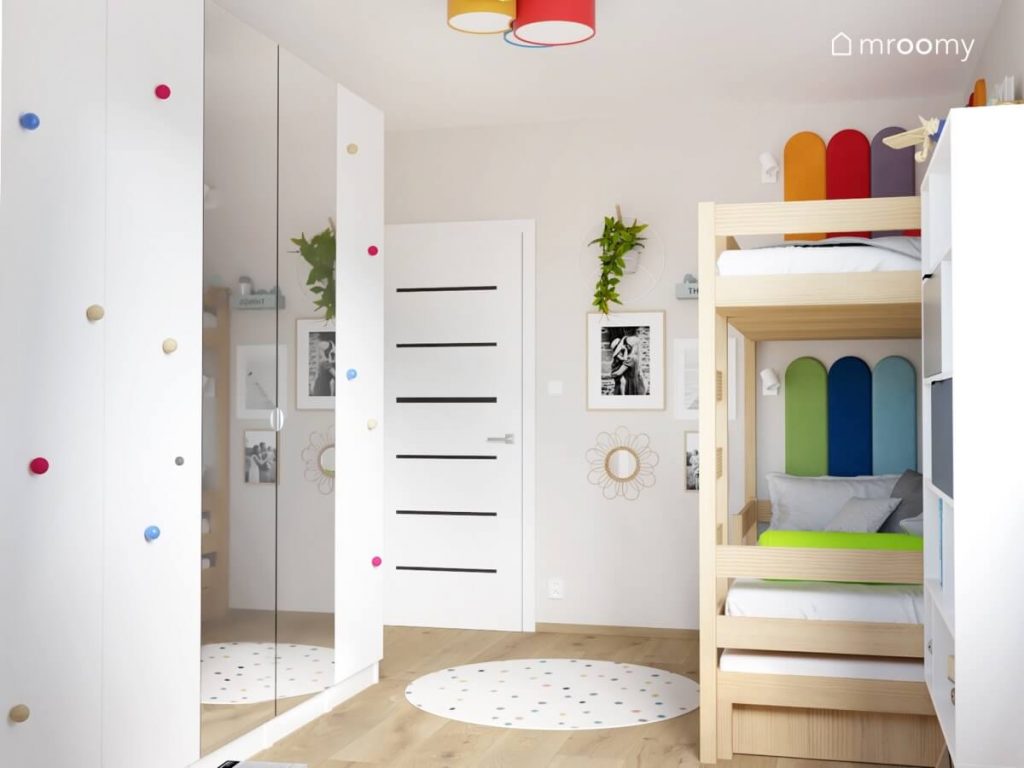 Duża szafa z lustrzanymi frontami i kolorowymi gałkami a także drewniane łóżko piętrowe w pokoju chłopca i dziewczynki