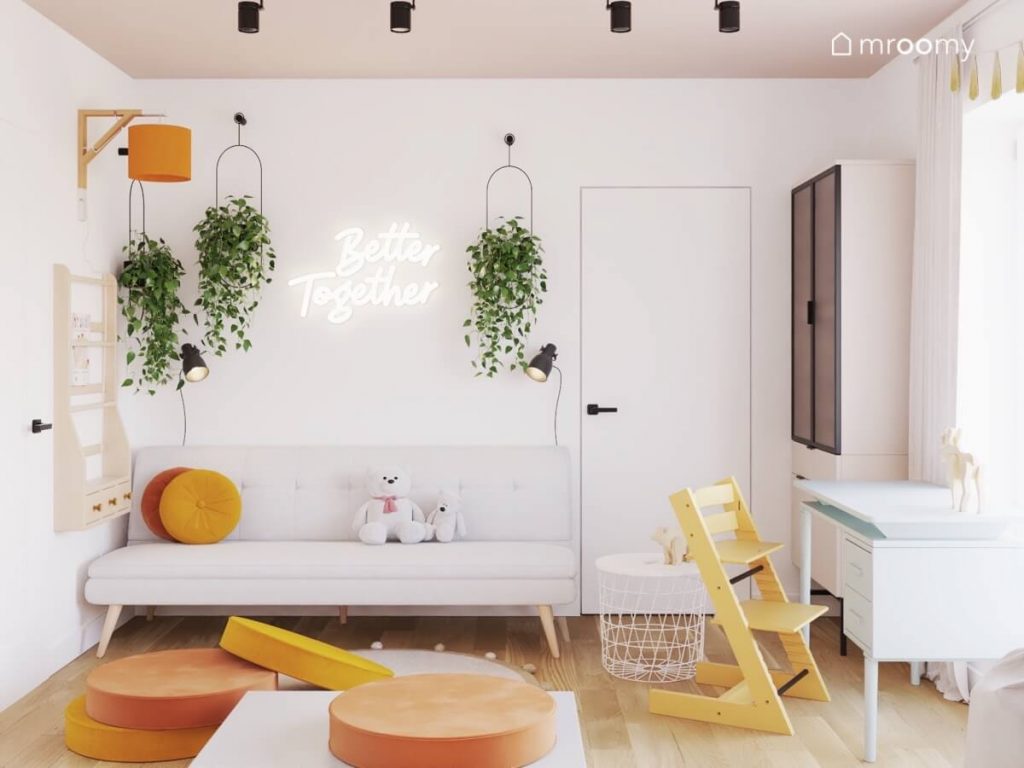 Biały pokój z beżowym sufitem dla dziewczynki a w nim jasne meble oraz żółte i pomarańczowe dodatki a także kwietniki