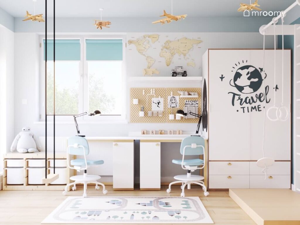 Strefa nauki w biało szarym pokoju dwóch chłopców a w niej dwa biało drewniane biurka organizery ścienne oraz mapa świata a obok szafa urozmaicona neklejką