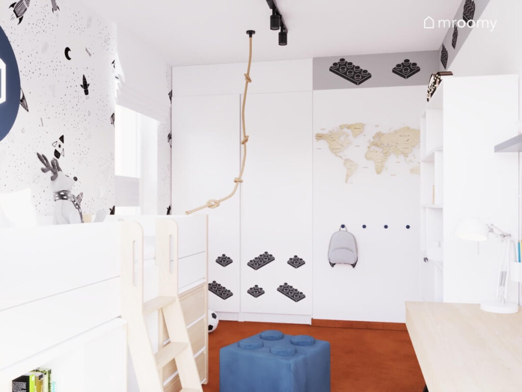 Jasny pokój dla sześciolatka a w nim białe meble granatowa pufka w kształcie klocka mapa świata i naklejki z motywem Lego