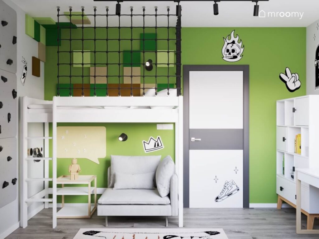 Strefa spania na antresoli uzupełniona panelami ściennymi w różnych kolorach a pod spodem szara sofa w zielonym pokoju dla chłopca