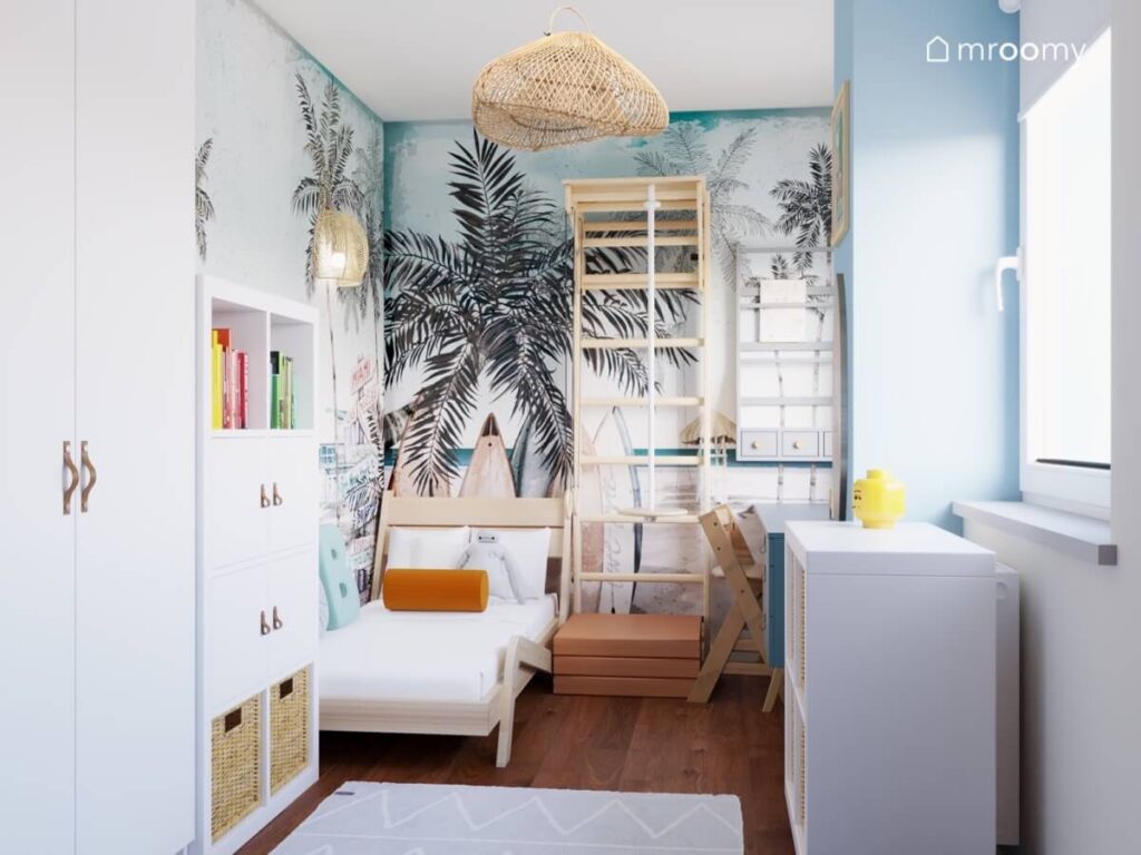 Niebieski pokój dla chłopca ze ścianami oklejonymi wakacyjną tapetą w palmy drewnianym łóżkiem drabinką gimnastyczną i białymi regałami