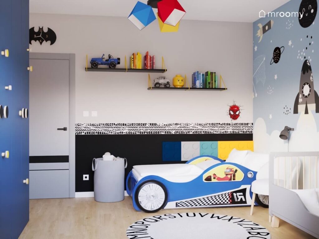 Szaro niebieski pokój dla dwóch chłopców z samochodem wyścigówką zegarem Batman oraz czarno żółtymi półkami