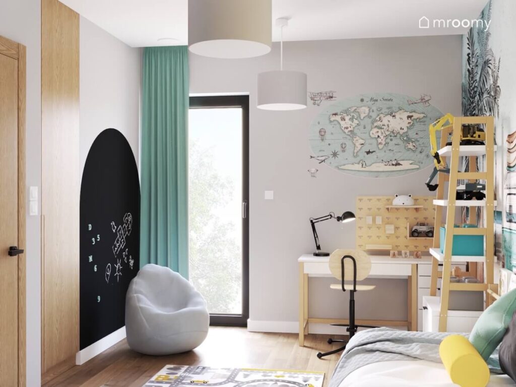 Szary pokój dla chłopca z biało drewnianymi meblami powierzchnią kredową pufą oraz mapą świata