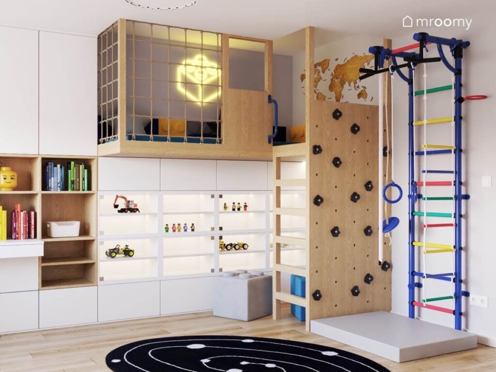 Jasny pokój dla chłopca z antresolą ścianką wspinaczkową oraz kolorową drabinką gimnastyczną oraz licznymi szafkami i półkami