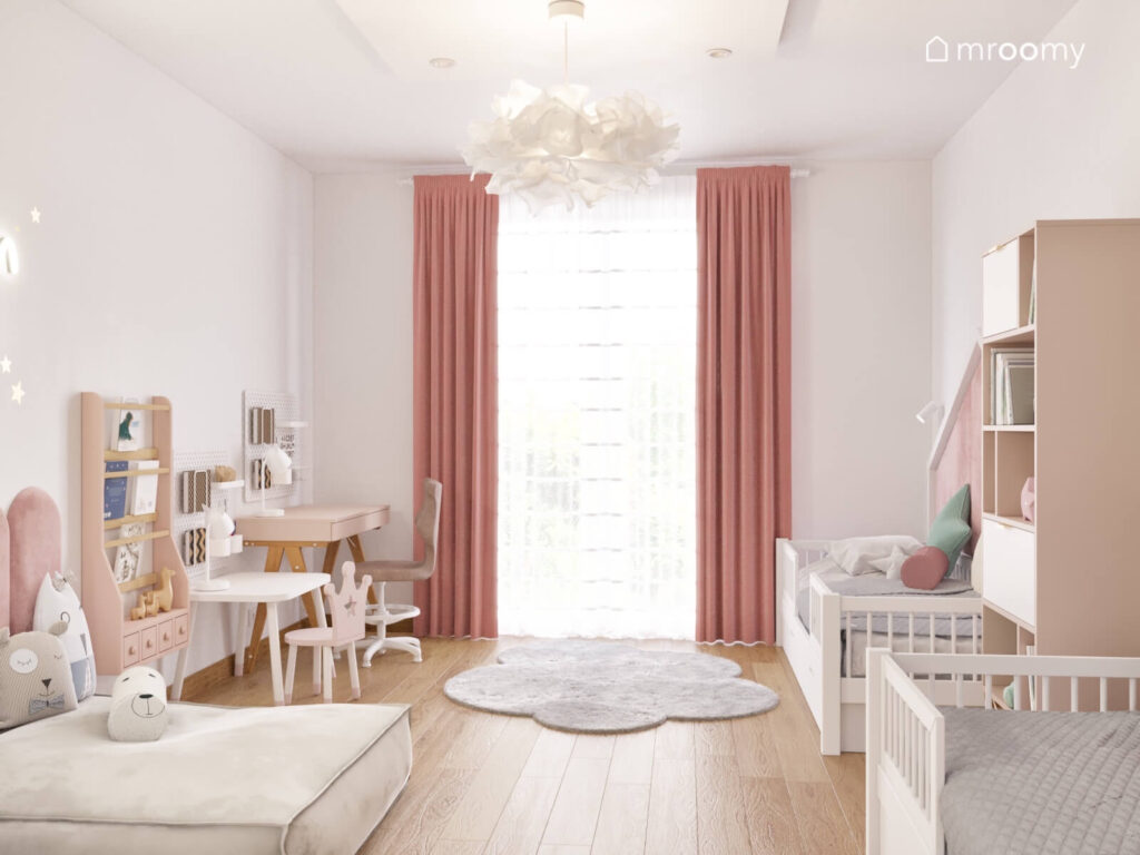 Biały pokój dla dwóch dziewczynek z białymi łóżkami biurkiem i stolikiem oraz dywanem chmurka i różowymi zasłonami