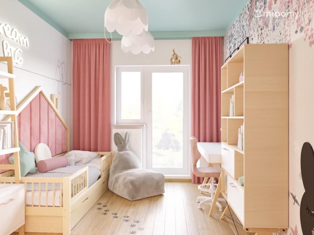 Jasny pokój dla dziewczynki z białymi ścianami i miętowym sufitem oraz białymi i drewnianymi meblami oraz pufą królik