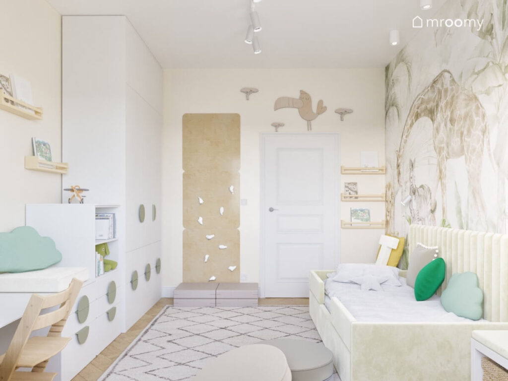 Jasny pokój dla malutkiego chłopca a w nim białe i drewniane meble ścianka wspinaczkowa oraz wzorzysty dywan